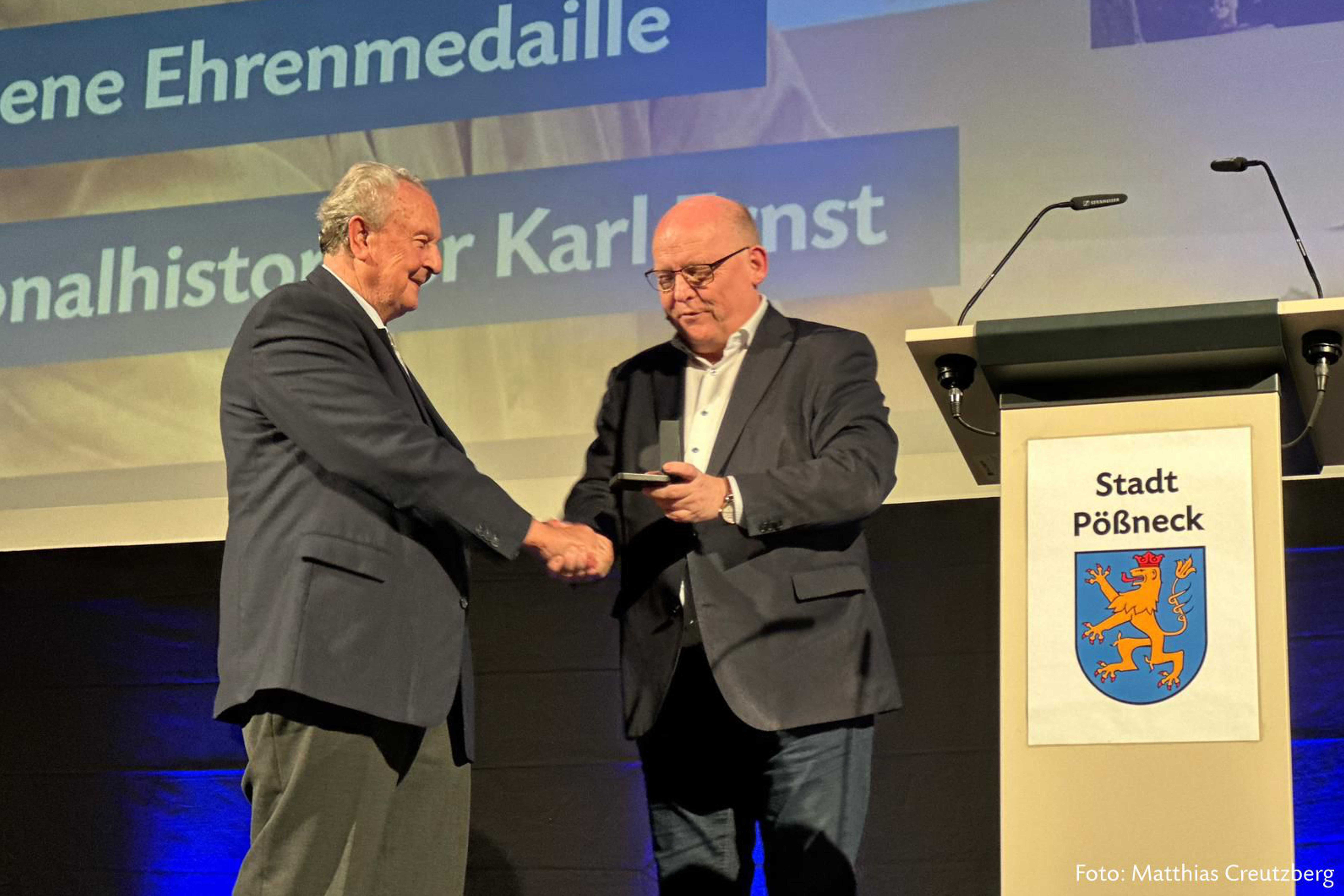 Jahresempfang_Goldene Ehrenmedaille Zwei Männer bei Medaillenübergabe auf Bühne