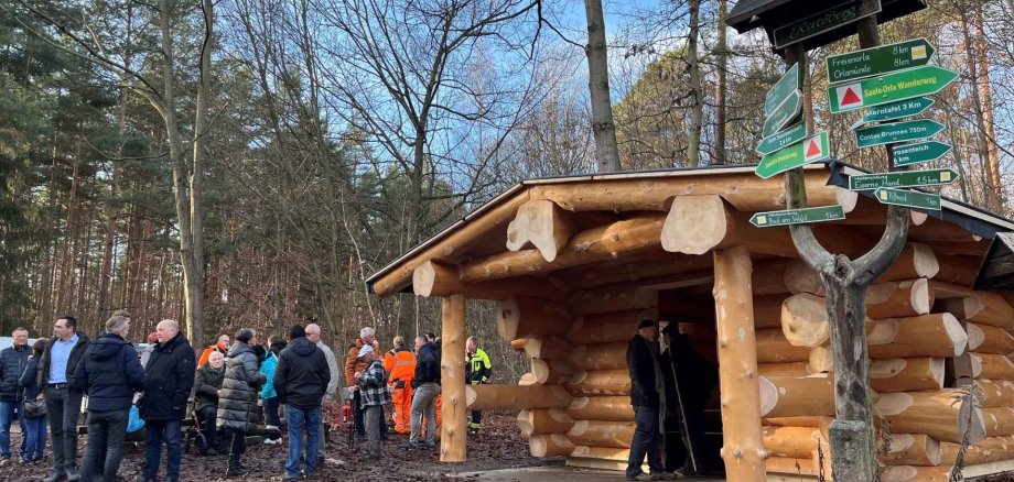 Schutzhütte in Blockbauweise mit Menschen davor
