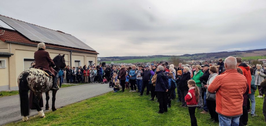 Pößnecker Osterspaziergang Menschentraube neben einem Mann als Goethe verkleidet auf einem Pferd