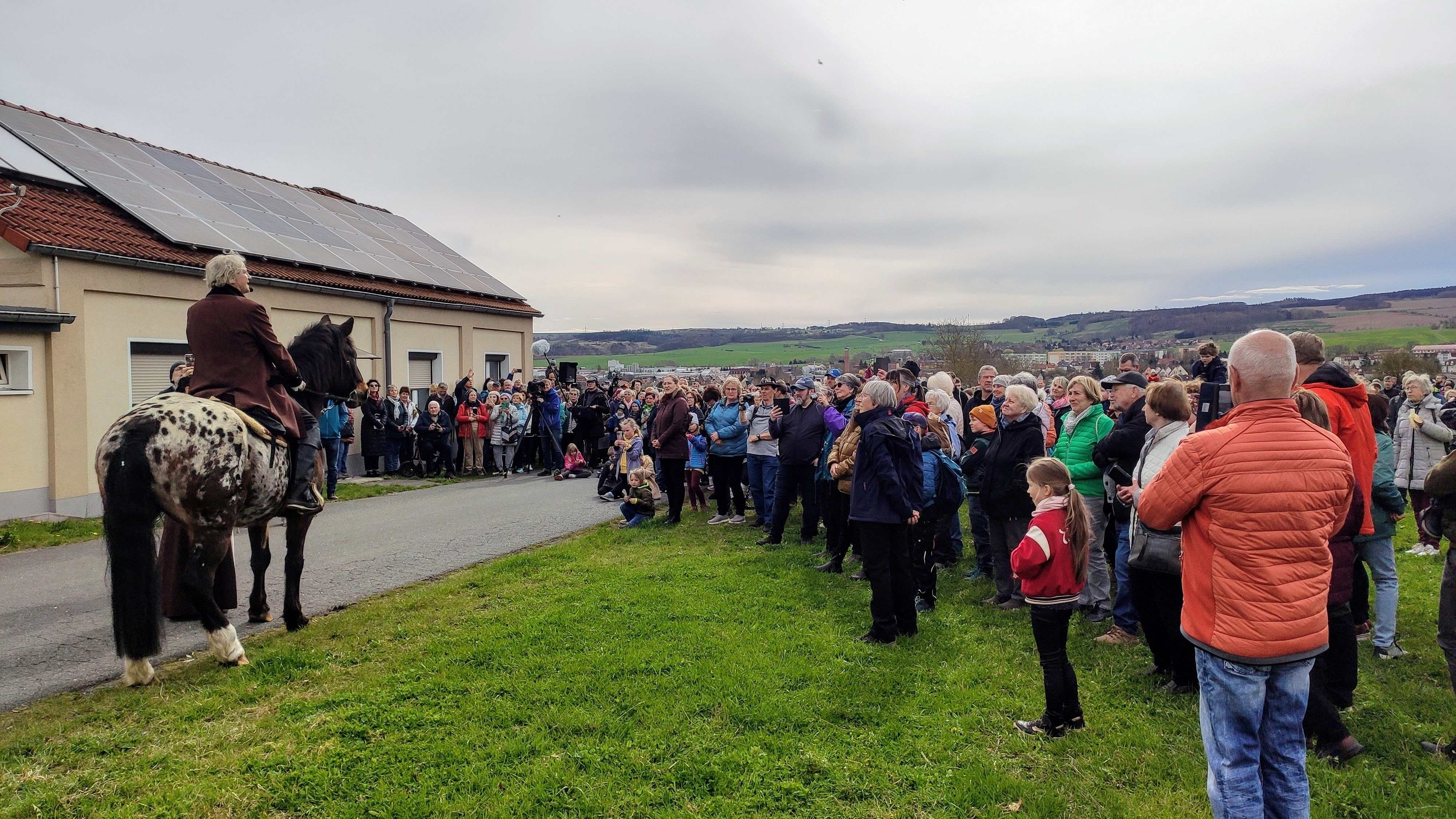 Menschentraube neben einem Mann als Goethe verkleidet auf einem Pferd