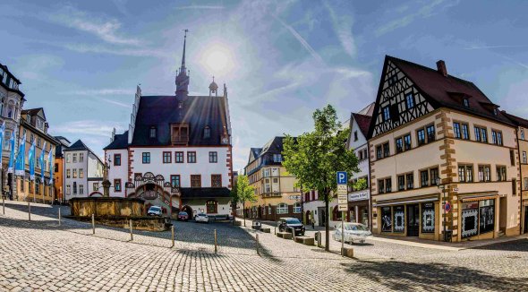 Blick auf das spätgotische Rathaus bei Sonnenschein, im Vordergrund schiefer Markt mit Marktbrunnen
