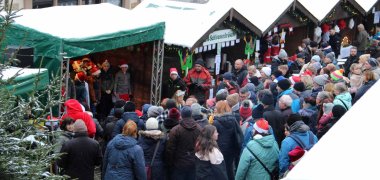 Adventsmarkt der Vereine schneebedeckte Stände und Bühne, davor Menschen
