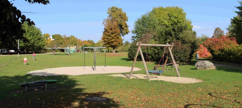 weiträumige Parkanlage mit Schaukel und Wippe
