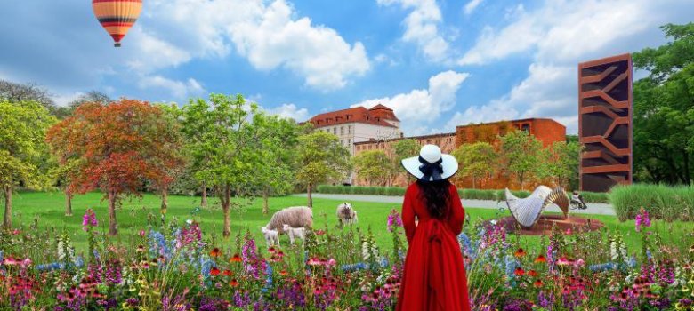 Frau mit roten Kleid steht vor einem Park