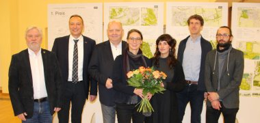 Sieben Personen, darunter zwei Frauen mit Blumenstrauß