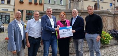 Fördermittelübergabe Regionalentwicklung 2026 Sechs Personen mit symbolischem Scheck vor dem Pößnecker Marktbrunnen