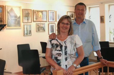 Mann und Frau eng nebeneinander in einem Raum mit zahlreichen Gemälden