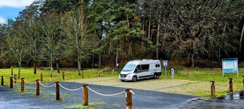Caravan lädt auf gepflastertem Stellplatz am Waldrand