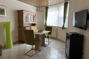 Blick in Wohnraum - Tisch mit zwei Stühlen, Fernseher, Schrank