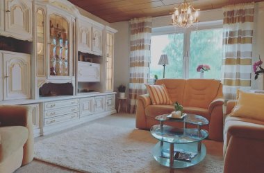Wohnzimmer mit heller Schrankwand und Sofa